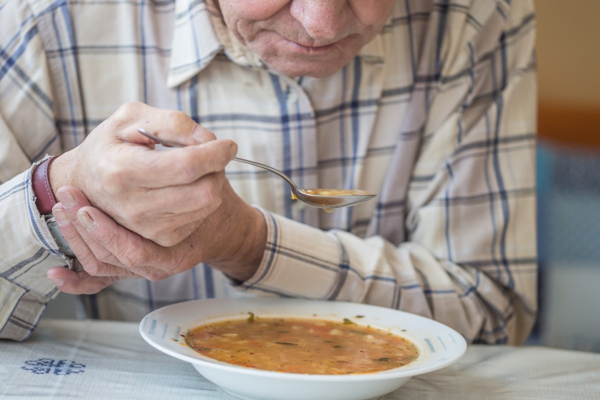 パーキンソン病の震えに対して、スープを食べ、手をかざす男性