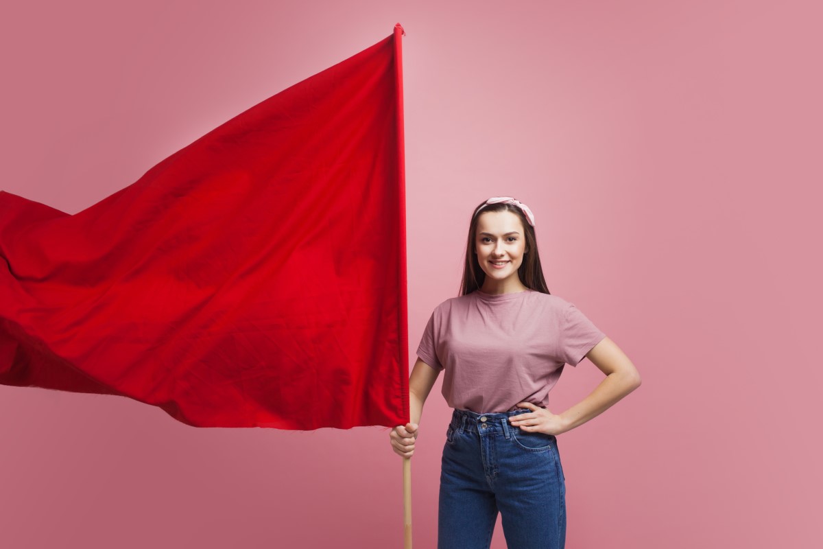 女性が大きな赤い旗を持って警告している。