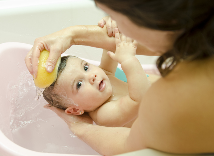 スポンジバスで赤ちゃんを洗う母親