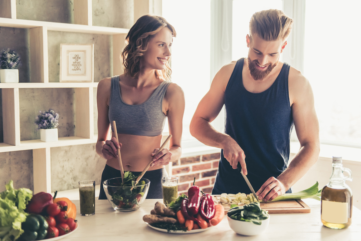 キッチンで健康的な食事を準備する男女。