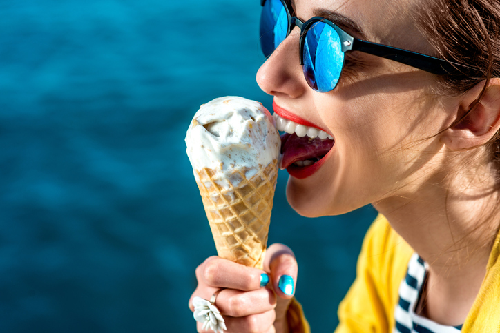 水辺でアイスクリームを舐めるサングラスの女