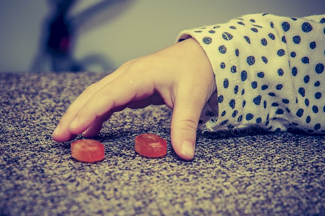 子供の手、2つの赤いキャンディー、悪い食習慣