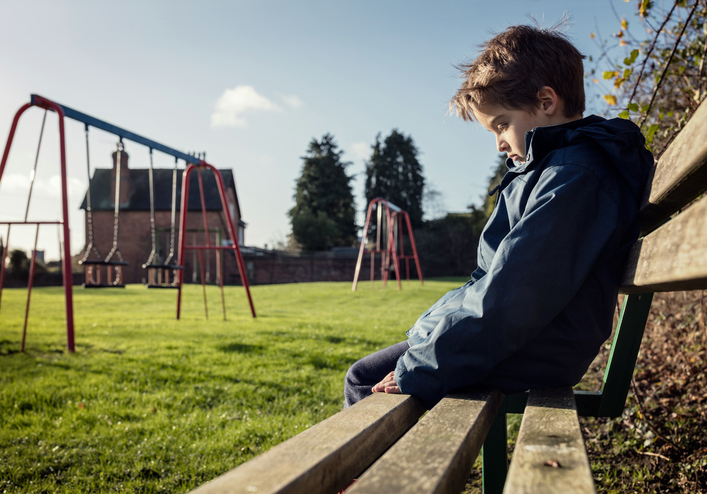 ベンチに一人で座る少年、悲しい、否定的な感情、遊び場、芝生、ブランコ