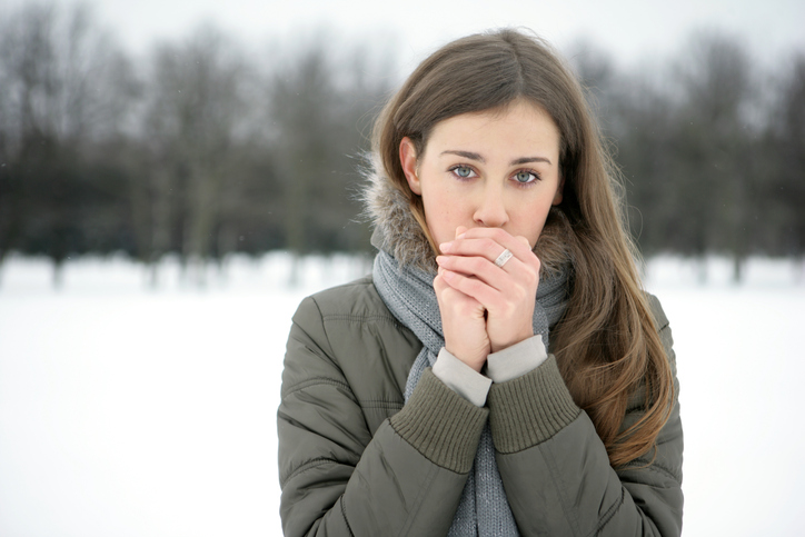 冷たい手足を吐息で温める女、外は雪、寒い、寒い